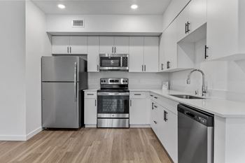 A modern kitchen with stainless steel appliances and wooden flooring.